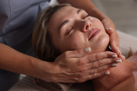Beautiful woman receiving facial massage in spa salon, closeup