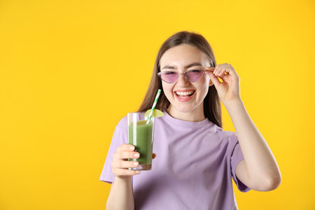 Woman with refreshing drink and straw on orange background, space for textの写真素材