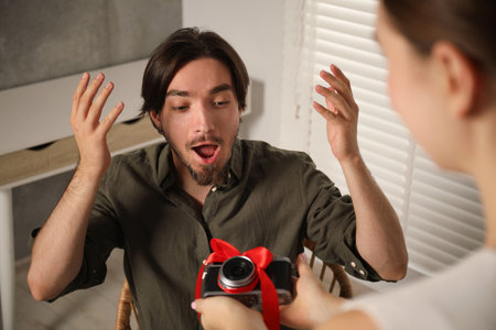 Dreams come true. woman gifting man camera at home, closeup