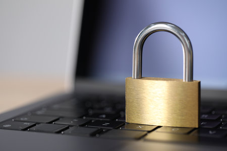 Cyber safety. Metal padlock and laptop on table, closeup. Space for textの写真素材