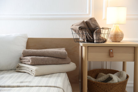 Stack of clean towels on bed linens and nightstand at homeの写真素材
