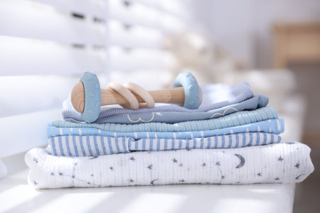 Stack of clean baby clothes and accessory on window sill indoors, closeupの写真素材