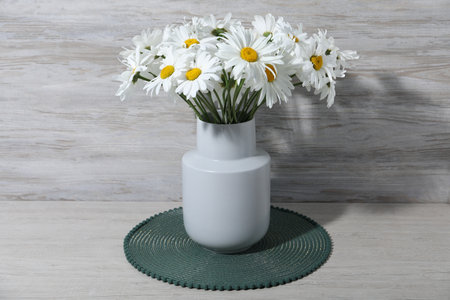Beautiful chamomile flowers in vase on grey wooden tableの写真素材