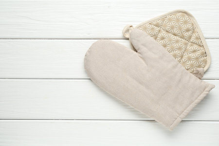 Oven glove and potholder on white wooden table, top view. Space for textの写真素材
