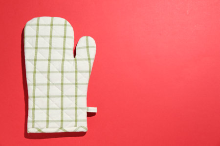 One oven glove on red background, top view. Space for textの写真素材