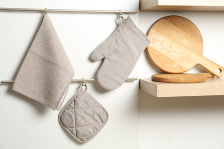 Oven glove, potholder and towel hanging on metal rack in kitchenの写真素材