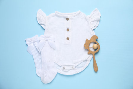 Stylish baby onesie and accessories on light blue background, flat layの写真素材