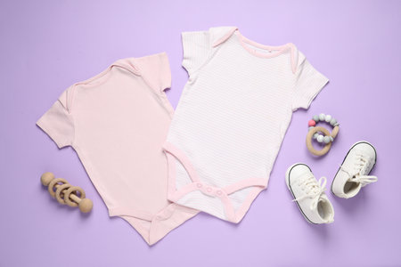 Stylish baby onesies and accessories on violet background, flat layの写真素材