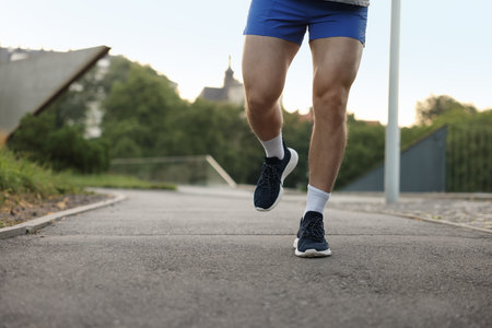 Athletic young man in sportswear running outdoors, closeup. Space for textの写真素材