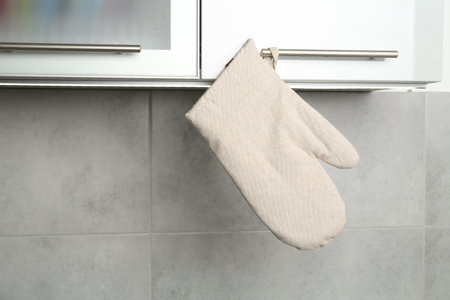 Oven glove hanging on handle of cabinet in kitchenの写真素材