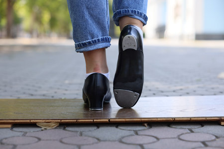 Teenage girl in tap shoes dancing outdoors, closeupの写真素材