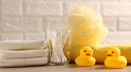 Baby bath accessories on wooden table against white brick wall, closeupの写真素材