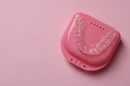 One clear aligner and retainer case on pink background, top view. Space for textの写真素材