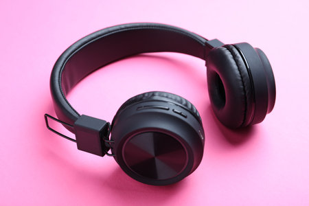Pair of stylish black headphones on pink background, closeupの写真素材