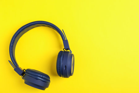 Pair of stylish blue headphones on yellow background, top viewの写真素材