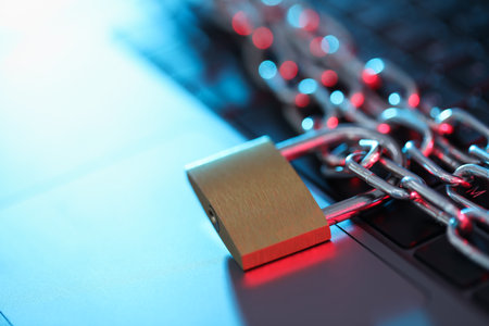 Cyber safety. Metal padlock with chain on laptop in color lights, closeupの写真素材