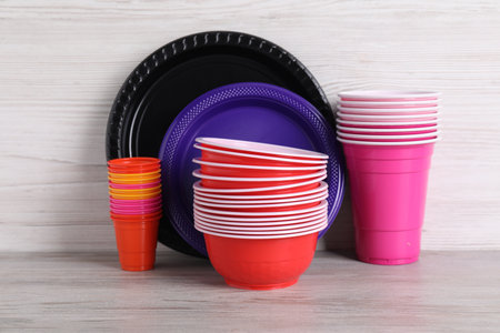 Set of disposable plastic tableware on light gray wooden table, closeupの写真素材