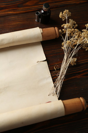 Old rolled scroll, dry flowers and inkwell on wooden table, above viewの写真素材