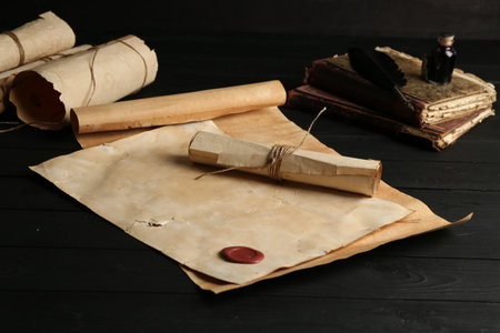 Many old rolled scrolls and books on black wooden table, closeupの写真素材