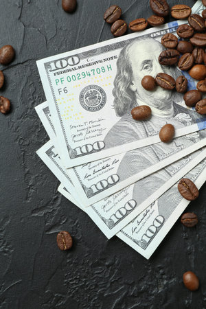 Dollar banknotes and roasted coffee beans on dark textured table, flat lay