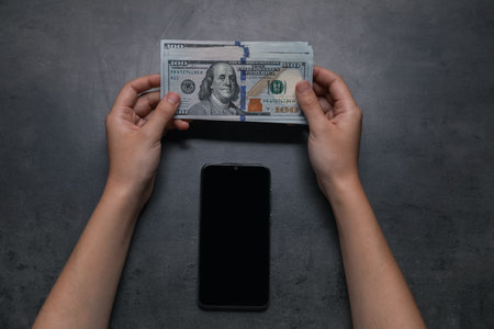 Woman with money and smartphone at gray table, top viewの写真素材