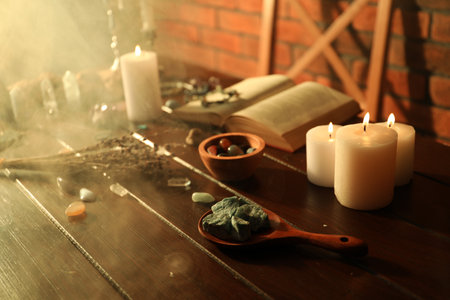 Healing stones, book, lavender and burning candles on wooden tableの写真素材