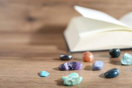 Different healing stones and book on wooden table, closeup. Space for textの写真素材