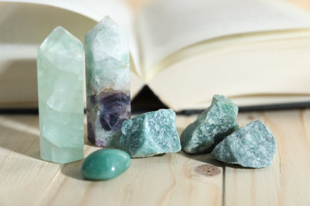 Different healing stones and book on wooden table, closeupの写真素材