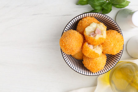 Delicious fried croquette balls in bowl and spices on white wooden table, flat lay. Space for textの写真素材