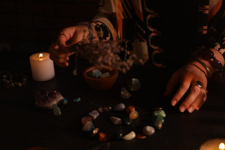 Woman doing ritual with healing stones at dark table, closeupの写真素材