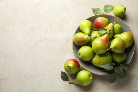 Fresh ripe pears and green leaves on light gray table, flat lay. Space for text