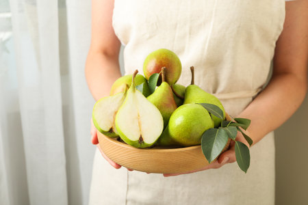 Woman with fresh ripe pears and green leaves indoors, closeupの写真素材