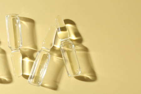 Glass ampoules with liquid on yellow background, flat layの写真素材
