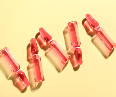 Glass ampoules with liquid on yellow background, flat layの写真素材