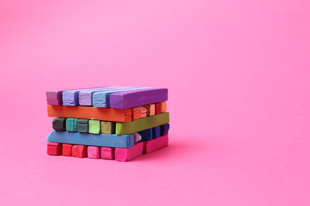 Many colorful chalk pastels on pink background. Space for text