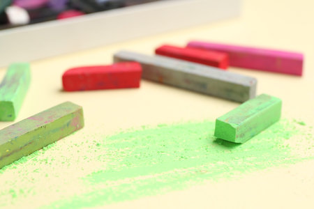 Many colorful chalk pastels on beige background, closeup
