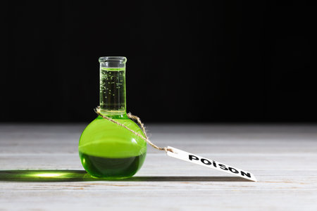 Flask of poison on wooden table against black backgroundの写真素材