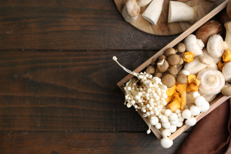 Different raw mushrooms and crate on wooden table, flat lay. Space for textの写真素材