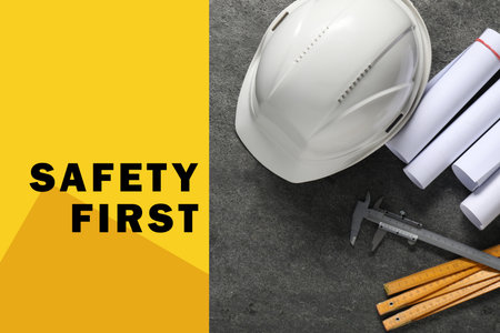 Safety first, poster. Hard hat, drafts, caliper and folding ruler on gray stone background, top viewの写真素材