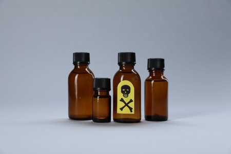 Bottles of poisons with warning sign on light gray background