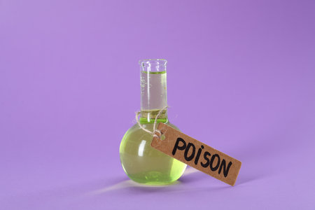 Glass flask with poison on violet background, closeupの写真素材