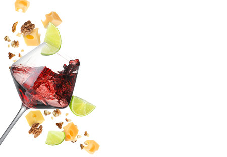 Glass with splashing red wine, cheese cubes and walnuts in air against white background