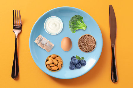 Plate with collection of different foods and cutlery on orange background, top view. Healthy eatingの写真素材