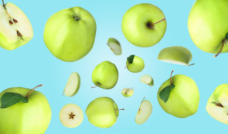 Fresh green apples swirling in air against light blue backgroundの写真素材