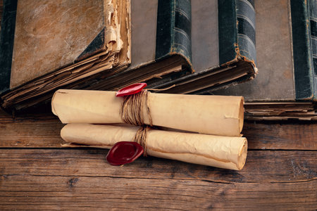 Old rolled paper scrolls and book on wooden tableの写真素材
