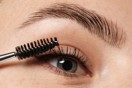 Woman applying mascara onto her eyelashes, closeup
