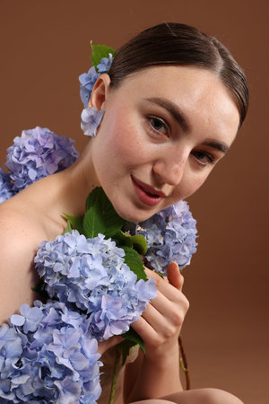 Beautiful young woman with hortensia flowers on brown backgroundの写真素材