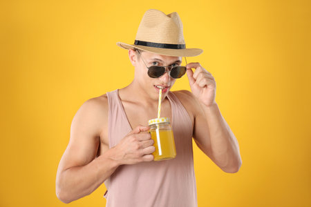 Man with juice and drinking straw on yellow backgroundの写真素材