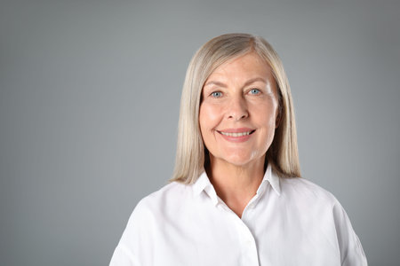 Portrait of beautiful senior woman on grey background. Space for text