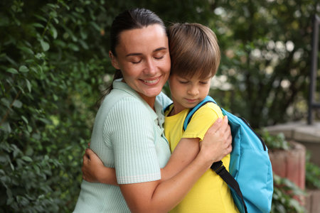 Mother hugging her son while taking him to school outdoorsの写真素材